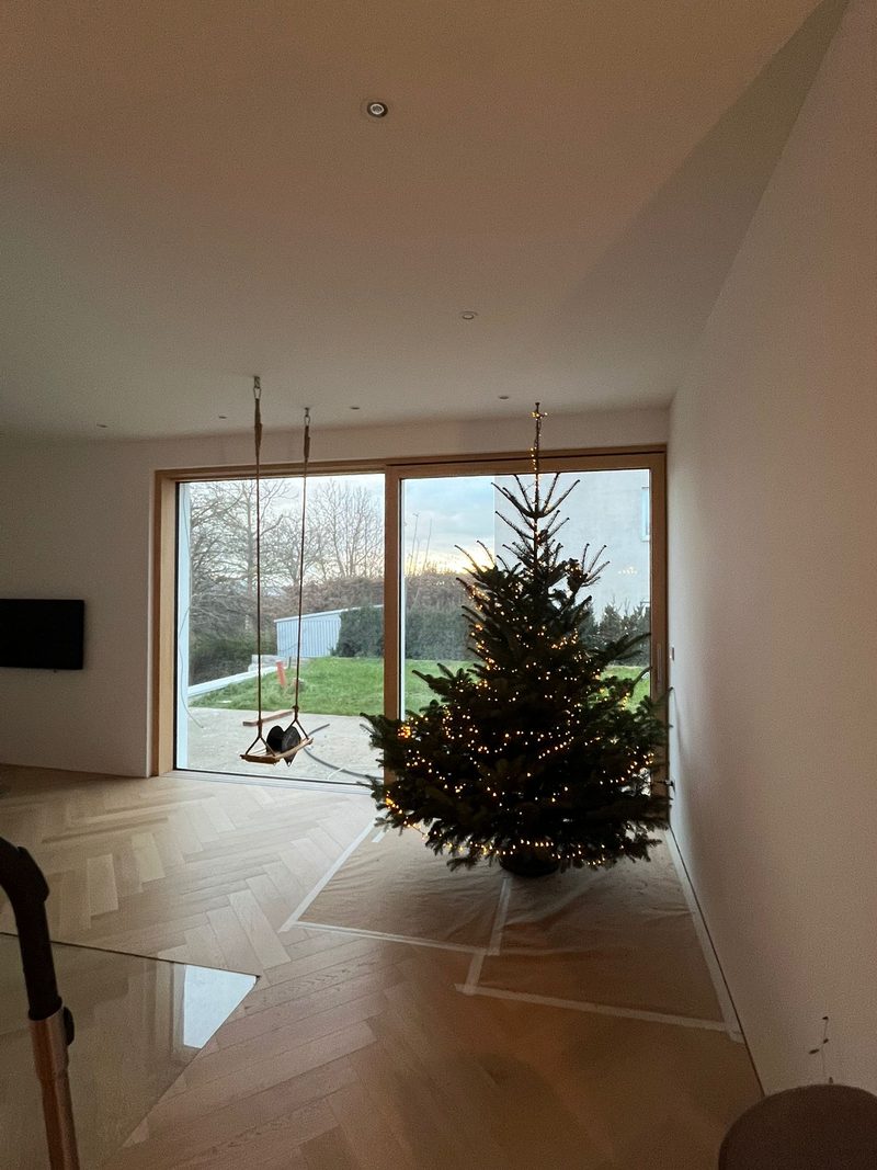 Wohnraum mit Fischgrätparkett und raumhoher Holz-Glas-Schiebetür mit Blick in den Garten
